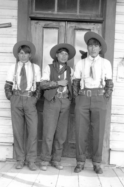 3 First Nations cowboys in front of Hoy store